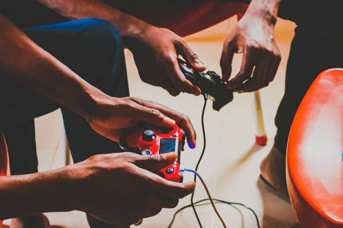 Two people holding game controllers with cables, seen close up