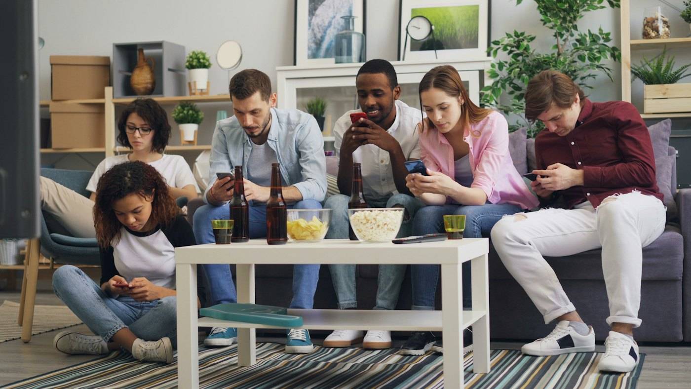 A group of friends on a sofa, each looking at a phone