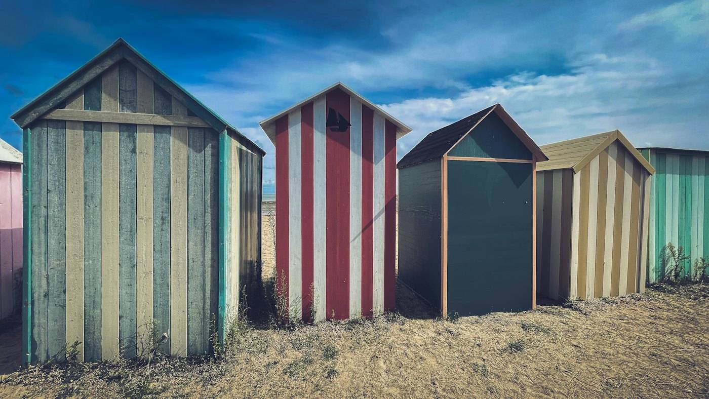 Striped beach huts on the sand under a cloudy sky