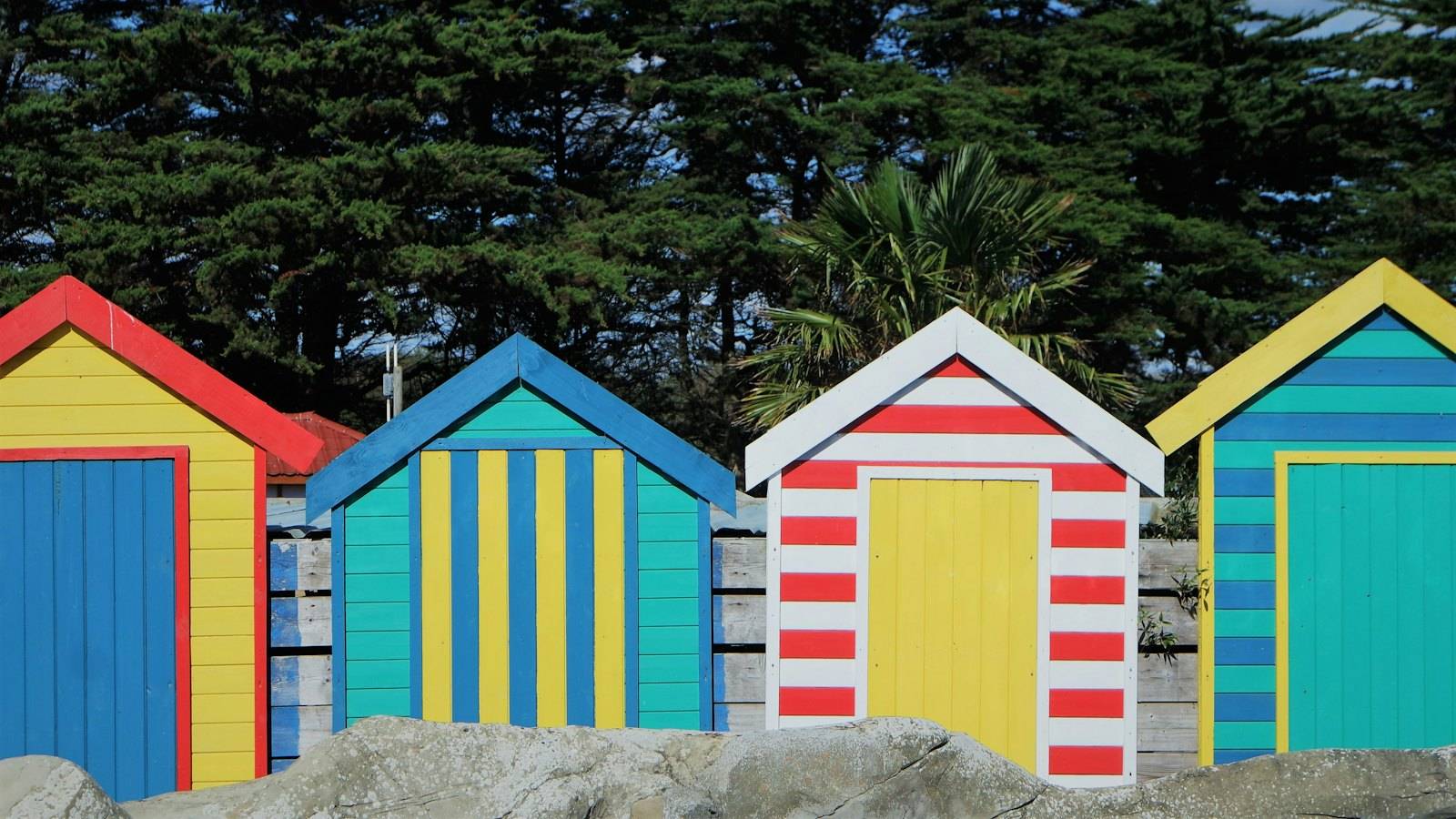 A row of striped beach huts in bright colours