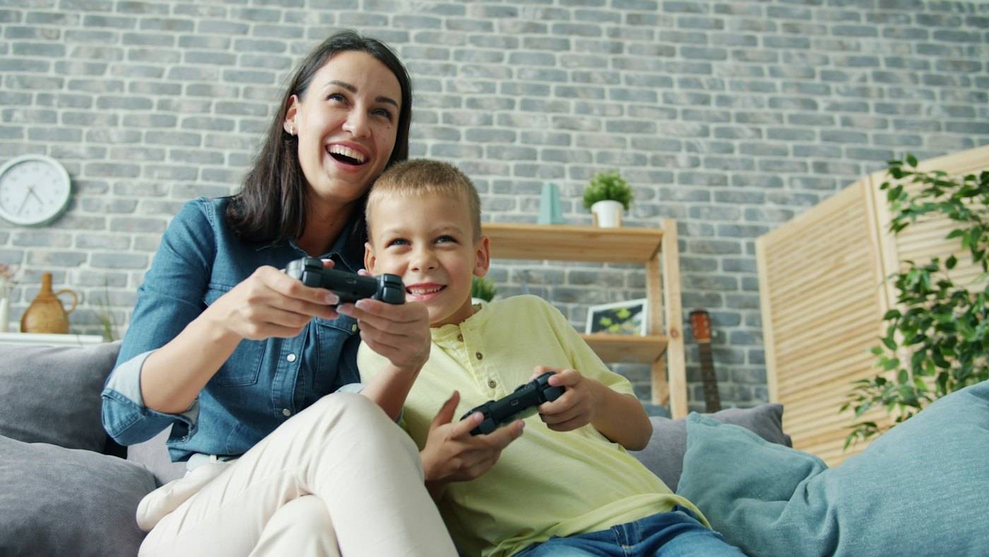 A mother and her son playing a video game on the sofa